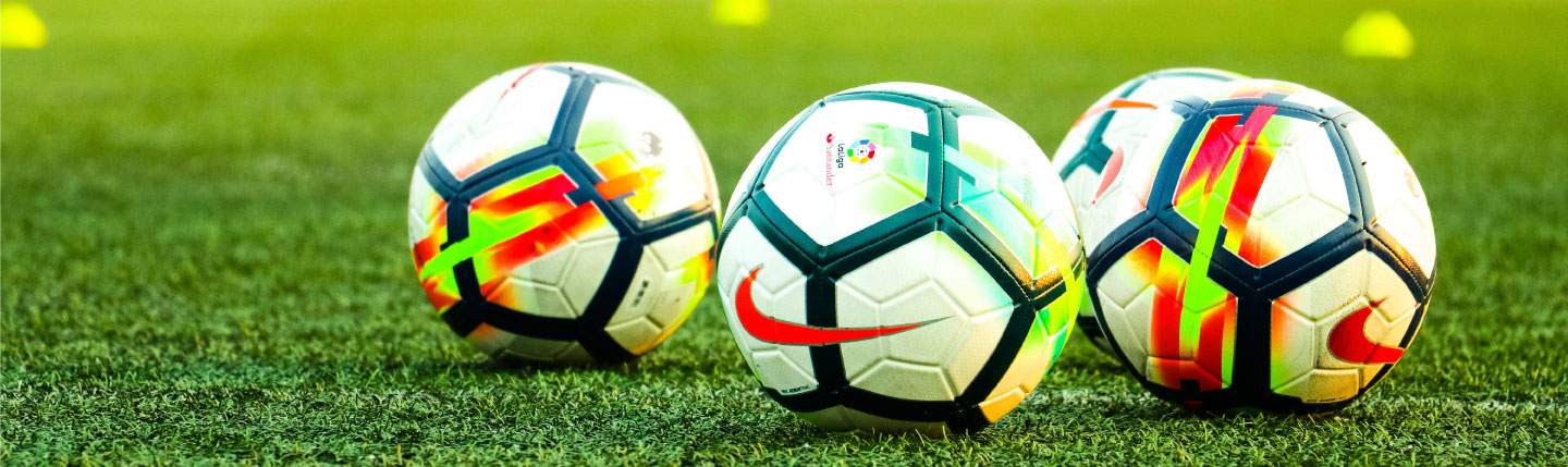Four footballs on a pitch
