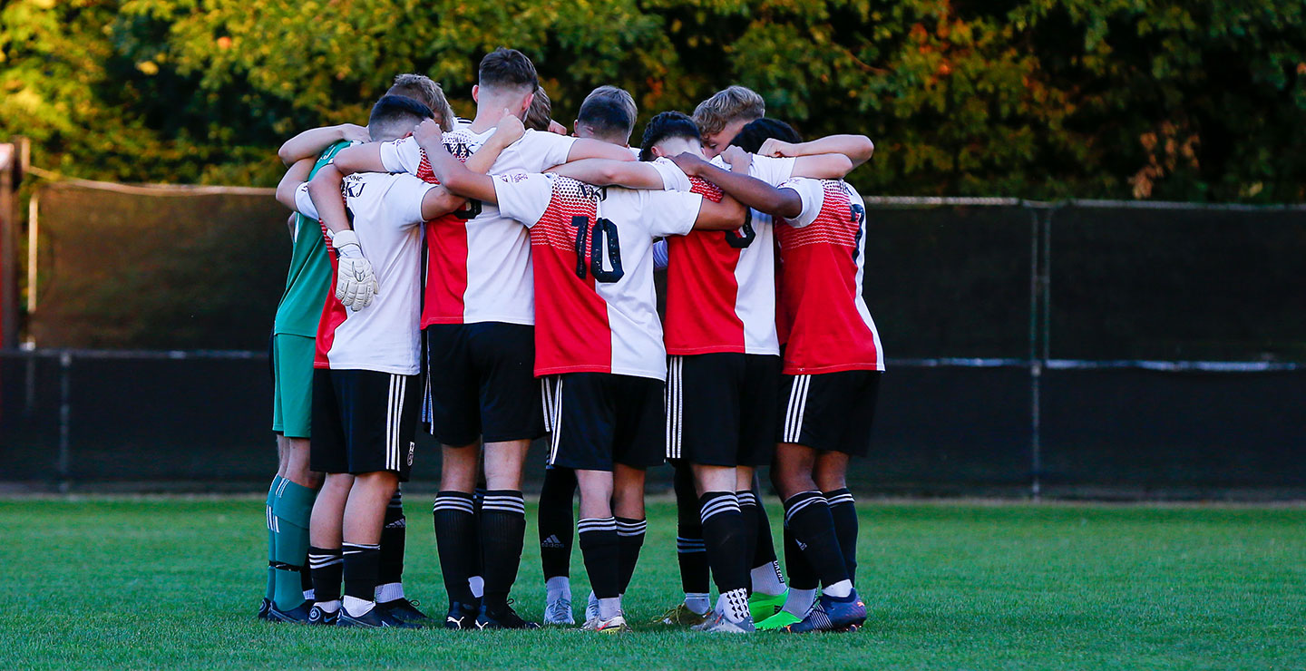 Woking FC Academy team, arms around each other and preparing to play